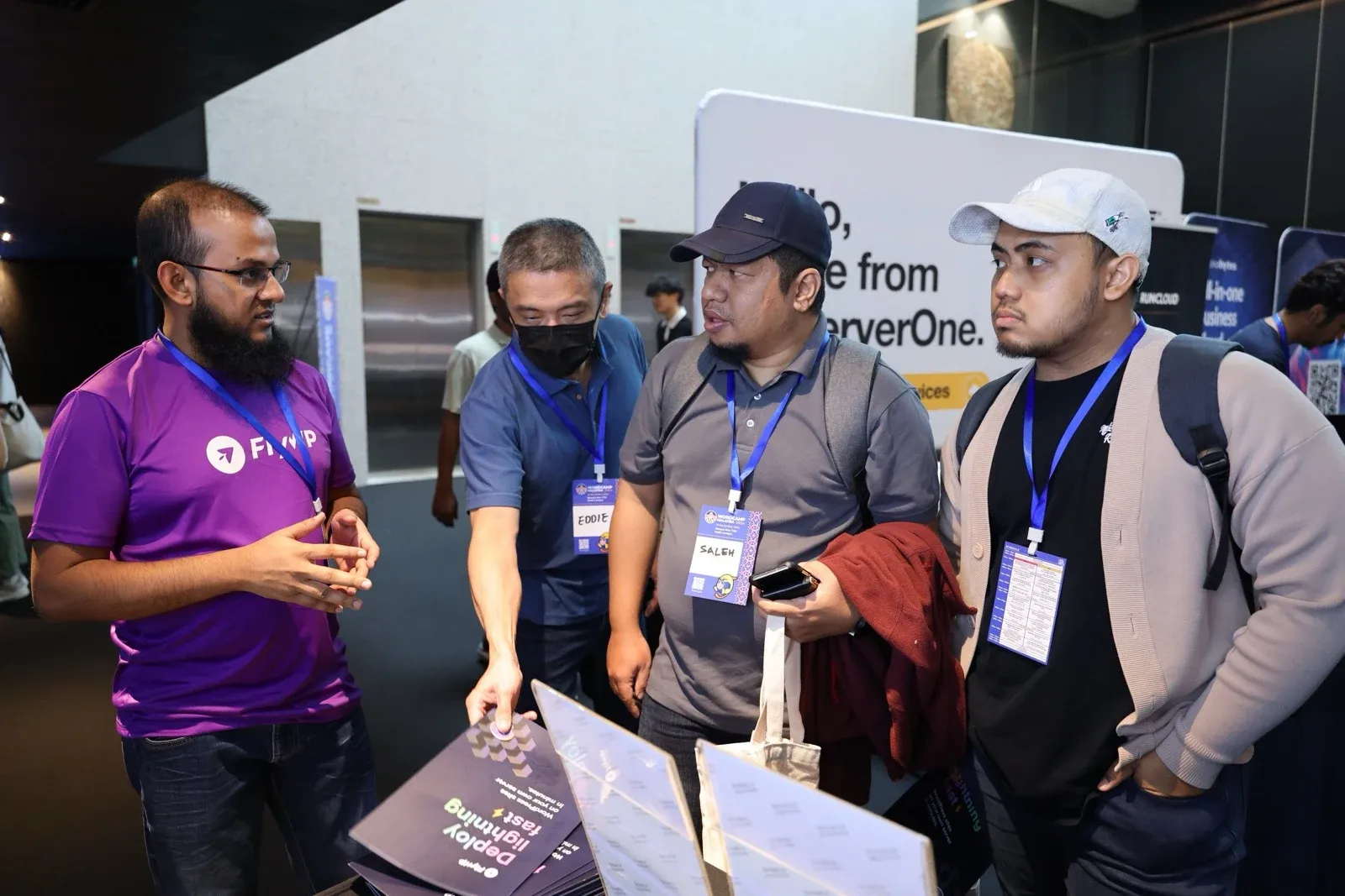 A weDevs team member talking with visitors at a conference booth
